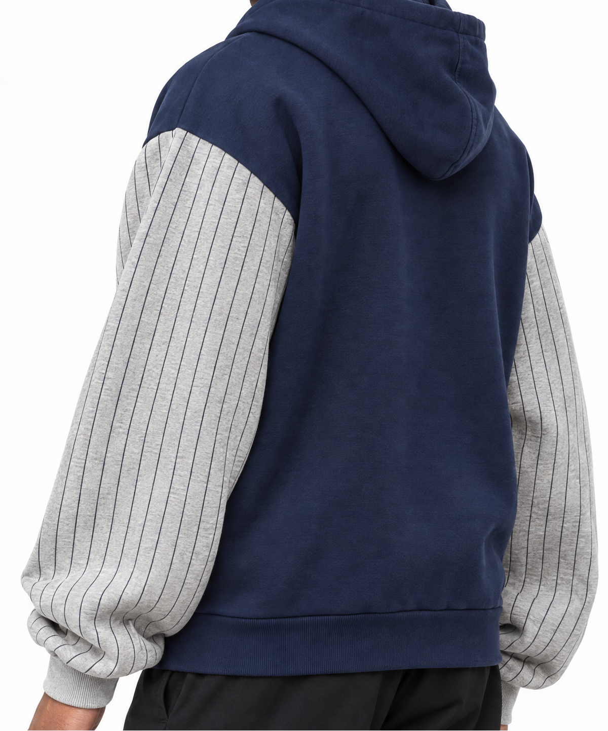 A person shown from the back wearing a color-block hoodie with a navy blue body and light gray pinstriped sleeves, paired with black pants, against a plain white background.